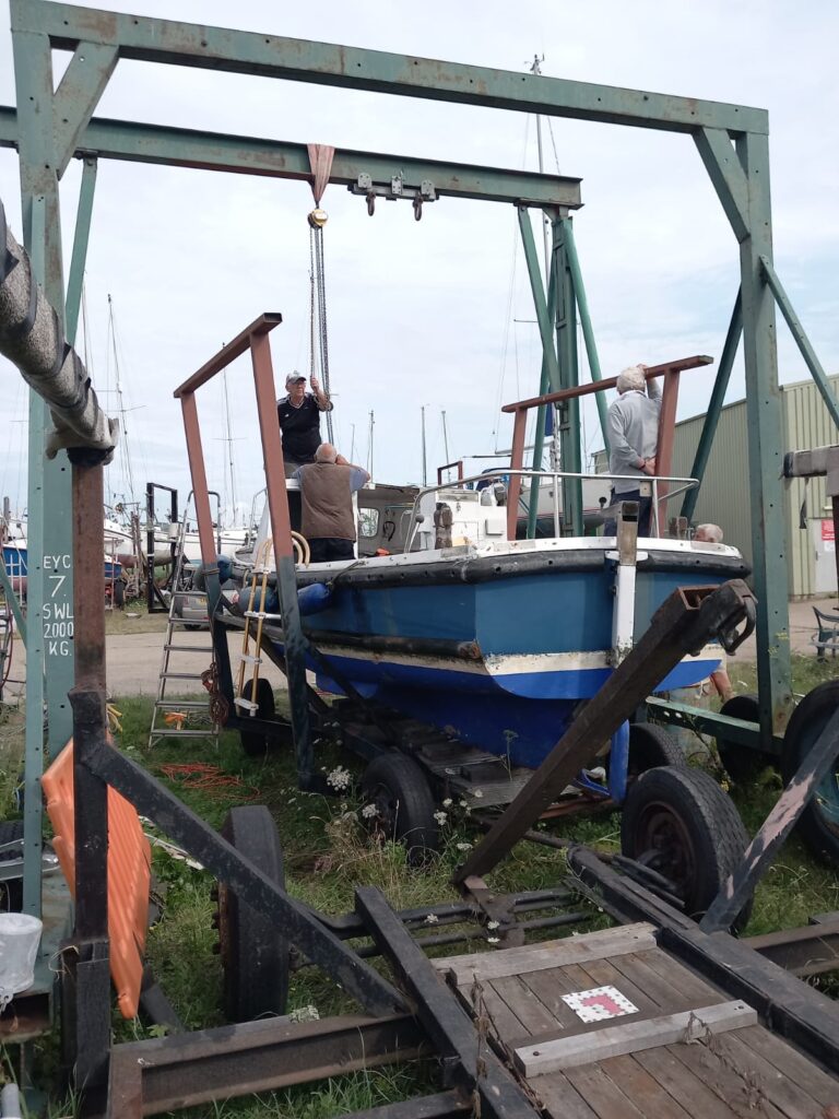 The boat hoist at Erith Yacht club with the Medway Recorder - a club utility boat in the hoist being worked on by several club members.